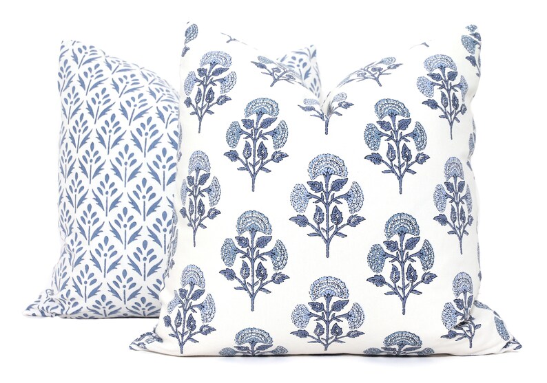 May include: Two blue and white patterned throw pillows. One pillow features a floral design, while the other has a more geometric pattern.