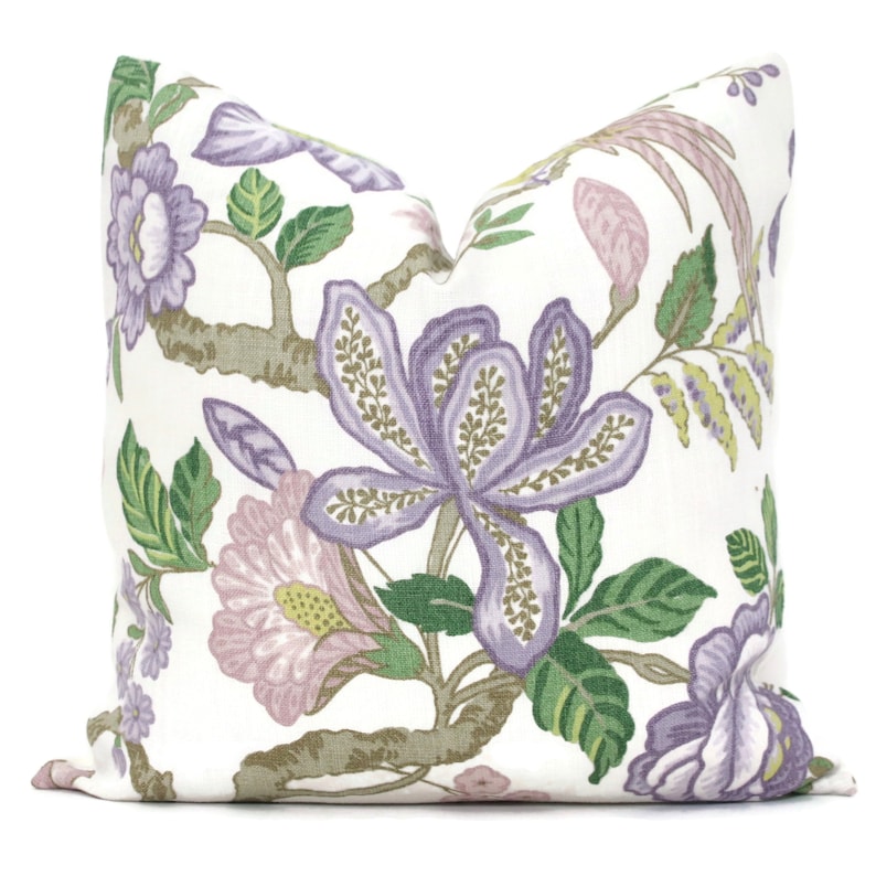 May include: A white cushion with a floral pattern in shades of purple, pink, and green. The flowers are stylised and have a vintage feel.
