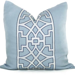 May include: A light blue throw pillow with a white and navy blue geometric pattern. The pattern is a repeating design of squares and diamonds.