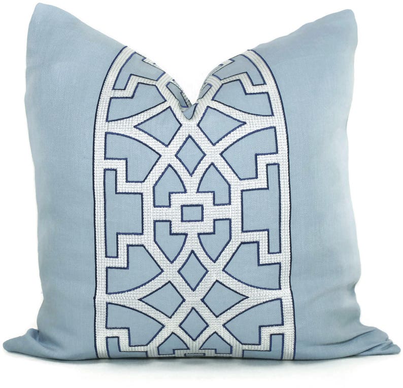 May include: A light blue throw pillow with a white and navy blue geometric pattern. The pattern is a repeating design of squares and diamonds.