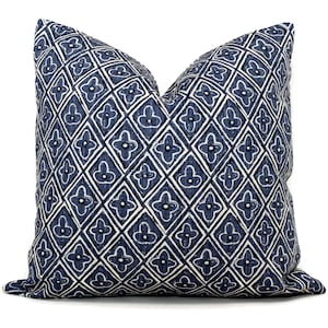 May include: A blue and white patterned throw pillow with a geometric design. The pillow is made of a soft, textured fabric and features a repeating pattern of diamonds and flowers.