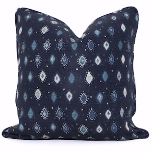 May include: A square decorative pillow with a dark navy blue background. The pillow features a repeating pattern of diamond shapes in shades of blue and white. The pillow is a soft, comfortable accent piece for a bed or sofa.