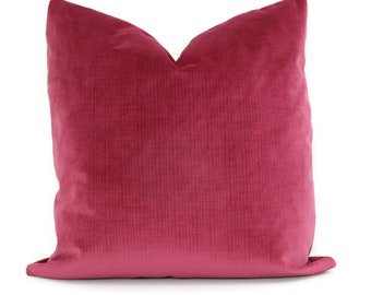 May include: A square, magenta-colored decorative pillow with a corduroy texture. The pillow is a solid color and has a soft, plush appearance. The pillow is designed for home decor and adds a pop of color to any room.