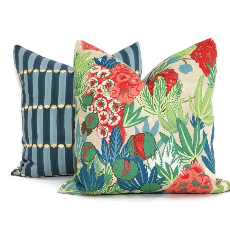 May include: Two decorative throw pillows, one with a blue and yellow striped pattern and the other with a floral pattern featuring red, green, and blue flowers on a beige background.