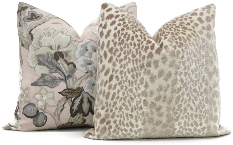 May include: Two decorative throw pillows, one with a pink background and a floral pattern in shades of gray and brown, and the other with a beige background and a brown leopard print.
