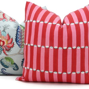 May include: Two decorative throw pillows, one with a blue background and a floral pattern, and the other with a pink and red striped pattern.