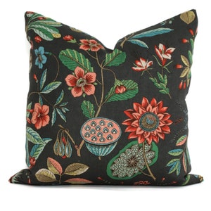 May include: A black pillow with a floral pattern featuring red, pink, green, and blue flowers. The pillow has a square shape and a soft, textured fabric.