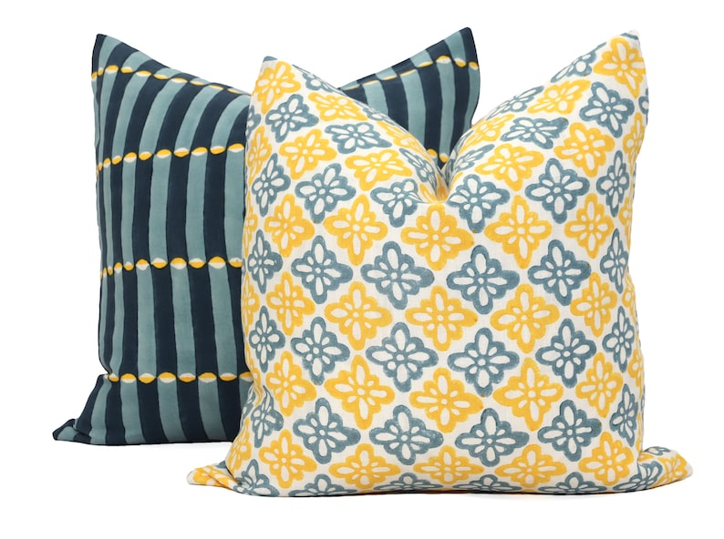 May include: Two decorative throw pillows with a geometric pattern. One pillow is blue and white with vertical stripes and yellow circles. The other pillow is white with a yellow and blue floral pattern.