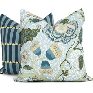 May include: Two decorative throw pillows with floral patterns. One pillow is blue with white stripes and yellow accents. The other pillow is light blue with a floral pattern in shades of blue, green, and yellow.