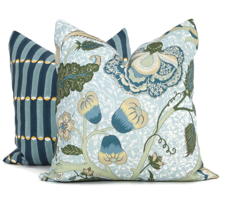 May include: Two decorative throw pillows with floral patterns. One pillow is blue with white stripes and yellow accents. The other pillow is light blue with a floral pattern in shades of blue, green, and yellow.