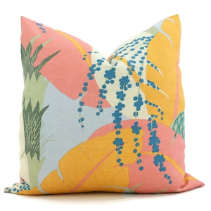 May include: Square decorative pillow with a colorful tropical leaf pattern. The design features large leaves in shades of coral, yellow, and light blue, with accents of teal and blue floral elements. The pillow is a square shape.