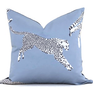 Op de afbeelding: Een blauw kussen met een wit en zwart luipaardprint. De luipaard springt in de lucht.