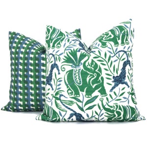 May include: Two decorative throw pillows with a green and blue geometric pattern and a white background with green and blue elephants, leopards, and foliage.