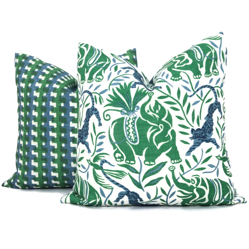 May include: Two decorative throw pillows with a green and blue geometric pattern and a white background with green and blue elephants, leopards, and foliage.