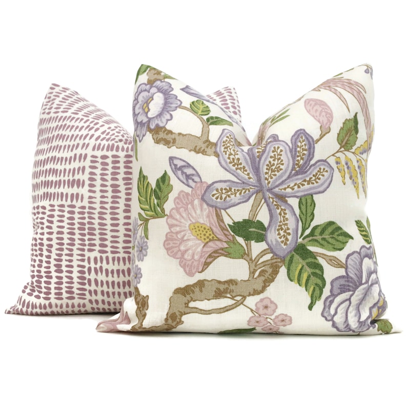 May include: Two decorative throw pillows, one with a floral pattern in shades of purple, pink, and green on a white background, and the other with a geometric pattern of small pink dots on a white background.