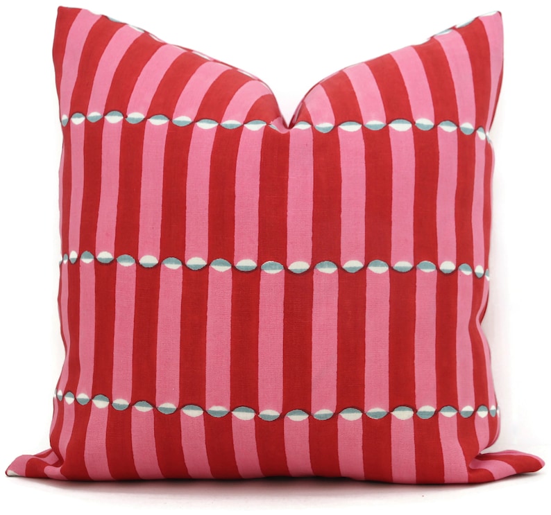 May include: Red and pink striped cushion with a white and blue geometric pattern.