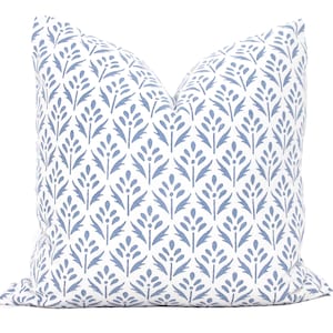 May include: A white pillow with a blue floral pattern. The pattern is a repeating design of stylized leaves and flowers.