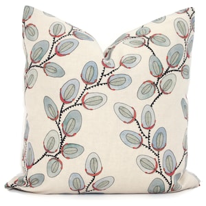 May include: Square decorative pillow with a cream-colored background. The pillow features a repeating pattern of blue and gray oval shapes connected by black, zigzagging lines with red accents. The pillow is a home decor item.