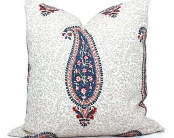 May include: Square decorative pillow with a white background and a large paisley design in blue, red, and white. The pillow has a floral pattern and is suitable for a bed or sofa.