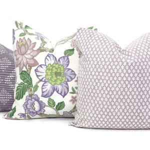 May include: Three decorative throw pillows with floral and geometric patterns. The pillows are in shades of purple, white and green.