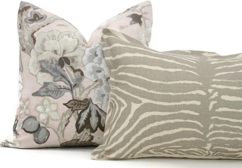 May include: Two decorative throw pillows, one with a pink background and a floral pattern in shades of gray, brown, and white, and the other with a beige background and a zebra stripe pattern.
