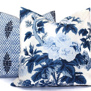 May include: Two decorative throw pillows. One pillow features a blue and white floral pattern with roses and foliage. The other pillow has a blue and white geometric trellis design with a floral motif.