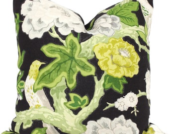 May include: A black pillow with a floral pattern featuring white, green, and yellow flowers, leaves, and a bird.