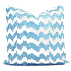 May include: A blue and white patterned throw pillow with a chevron design. The pillow is made of a soft, textured fabric.