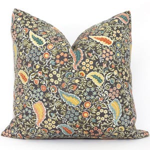 Puede incluir: Una almohada decorativa con un patrón floral en tonos marrones, verdes, amarillos, naranjas y azules. La almohada tiene un diseño tipo paisley con detalles intrincados.