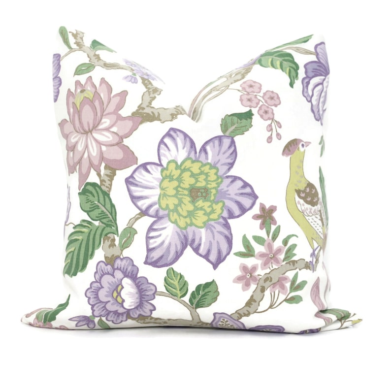May include: A white pillow cover with a floral pattern featuring purple, pink, green, and yellow flowers and a bird. The floral design is reminiscent of a traditional Asian style.
