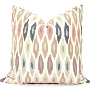 May include: A decorative throw pillow with a white background and a geometric pattern in shades of pink, brown, and gray.