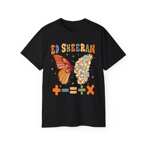 Peut inclure: T-shirt noir avec un motif de papillon. Une aile est orange et rose, l'autre est faite de marguerites blanches. Le texte "ED SHEERAN" est arqué au-dessus du papillon en lettres colorées. Des symboles mathématiques sont en dessous.