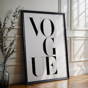 Può includere: Una stampa artistica rettangolare con cornice nera che presenta la parola VOGUE in caratteri tipografici serif neri, grandi e in grassetto, su uno sfondo bianco. La stampa è posizionata verticalmente, mostrando un design pulito e contrastato.