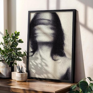 Puede incluir: Una impresi&oacute;n art&iacute;stica en blanco y negro enmarcada que presenta una imagen borrosa de una persona. La obra de arte se exhibe sobre una superficie de madera, junto a una planta en maceta y un portal&aacute;pices con l&aacute;pices.