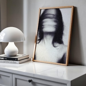 Puede incluir: Una l&aacute;mpara de mesa blanca con forma de hongo se encuentra sobre una pila de libros con los t&iacute;tulos "TOM FORD" y "TOM FORD GENTLE LIVING". Un retrato en blanco y negro enmarcado con un rostro borroso se apoya contra una pared. La escena est&aacute; ambientada en una c&oacute;moda blanca.