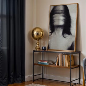 Puede incluir: Una escena de sal&oacute;n moderno con un retrato en blanco y negro con marco dorado, una l&aacute;mpara esf&eacute;rica dorada y una estanter&iacute;a de metal negro y madera con libros. Cortinas negras enmarcan una ventana.