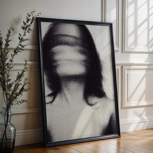 May include: A rectangular black-framed wall art piece featuring a grainy, high-contrast black and white pointillist portrait of a figure with obscured facial features, presented in a vertical orientation with a textured, speckled visual effect.