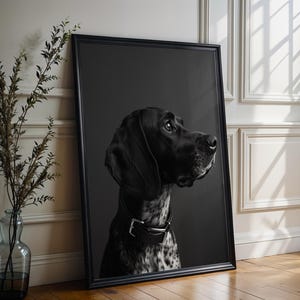 Può includere: Ritratto in bianco e nero incorniciato di un cane. Il cane ha un mantello nero, orecchie flosce e un collare di cuoio. Lo sfondo è grigio scuro. La cornice nera è appoggiata a un muro bianco.