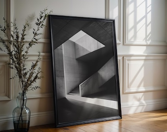 May include: A black framed wall art print featuring a monochromatic architectural photograph of a concrete staircase and geometric interior structure with sharp shadows and light contrasts, displayed in a vertical rectangular orientation.