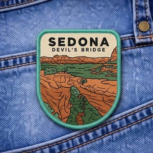 May include: A patch featuring a landscape illustration of Sedona's Devil's Bridge. The patch has a teal border and the text "SEDONA DEVIL'S BRIDGE" at the top. The design includes red rock formations and green vegetation.