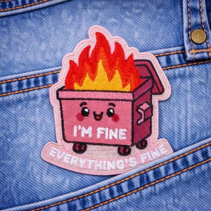 May include: Embroidered patch featuring a pink dumpster on fire with the text "I'M FINE" and "EVERYTHING'S FINE". The patch has a light pink border and is set against a blue denim background.