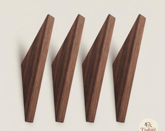 May include: Four triangular wall hooks made of dark brown wood with a visible grain pattern. Each hook features a sharp angled design and a smooth finish. A small circular logo with the text Craftora Atelier is visible in the bottom right corner.
