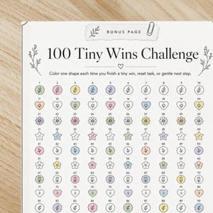 May include: A printable "100 Tiny Wins Challenge" sheet. The sheet features a grid of 100 shapes, including hearts, flowers, and stars, each with a number. The text "100 Tiny Wins Challenge" is at the top, with instructions below.