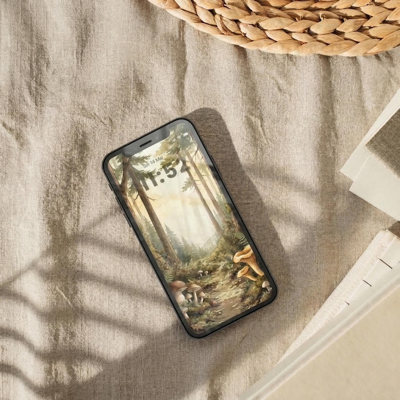 Lifestyle mockup of an Enchanted Forest cottagecore phone theme on a smartphone, featuring botanical woodland wallpaper with trees, mushrooms, and warm neutral styling.