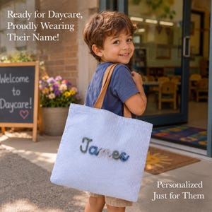 May include: A light blue and white seersucker tote bag with tan straps, featuring the name James embroidered in multi-colored yarn letters. The text on the image reads: Ready for Daycare, Proudly Wearing Their Name! Personalized Just for Them.