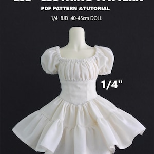 May include: A white doll dress with a square neckline and puffed sleeves. The dress has a fitted bodice and a flared skirt. The text "BJD CLOTHING PATTERN" and "PDF PATTERN & TUTORIAL" are at the top. The text "1/4 BJD 40-45cm DOLL" is also visible.