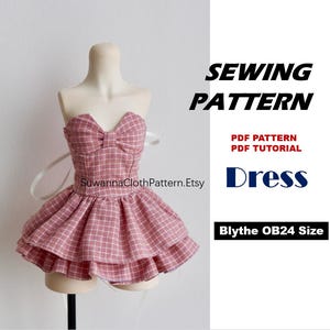 Könnte beinhalten: Ein trägerloses Kleid mit rosa-weißem Karomuster für eine Puppe, mit einem schleifenförmigen Oberteil und einem zweistufigen Rüschenrock. Der Text lautet SEWING PATTERN, PDF PATTERN, PDF TUTORIAL, Dress, Blythe OB24 Size und SuwannaClothPattern.Etsy.