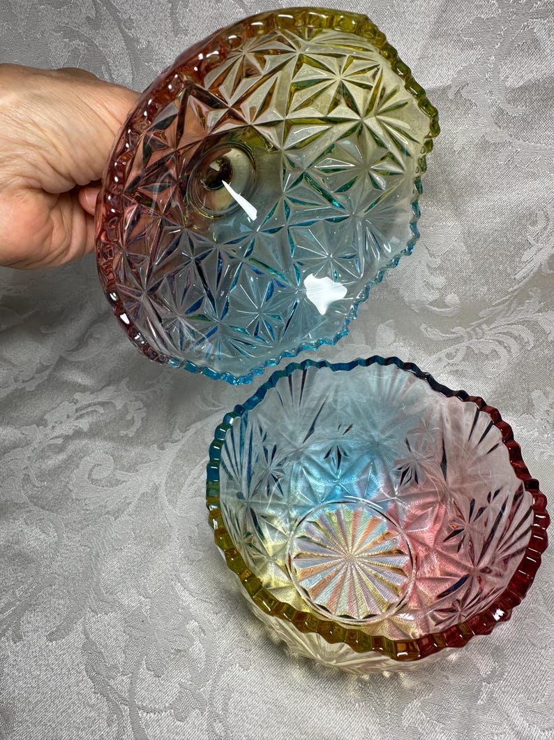 May include: Two iridescent glass bowls with a starburst pattern. The bowls have a scalloped edge and transition from red to yellow to blue. The bowls are likely for serving or display.