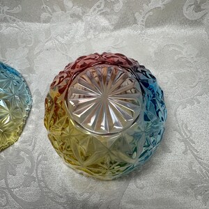 May include: A colorful glass bowl with a diamond pattern. The bowl transitions from red to yellow to blue, creating a rainbow effect. The bowl is likely for serving or display.
