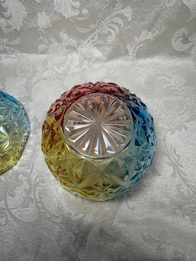 May include: A colorful glass bowl with a diamond pattern. The bowl transitions from red to yellow to blue, creating a rainbow effect. The bowl is likely for serving or display.